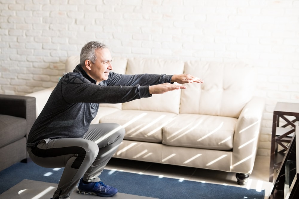 Older man doing squats in living room